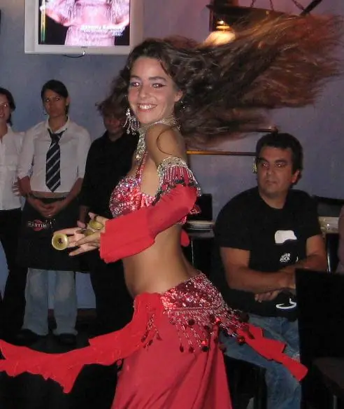Ana a sorrir a meio de uma volta, com um traje vermelho e o cabelo ao vento, durante uma atuação ao vivo